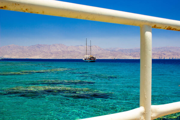 cruise ship summer vacation time Re sea water Gulf of Aqaba Middle East region landscape scenic view with rustic metal fence white frame foreground