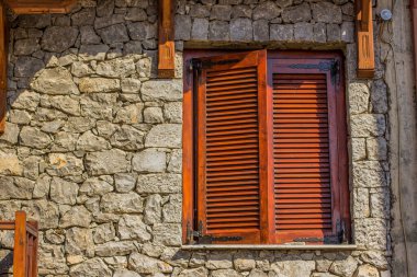 Ortaçağ ahşap pencere çerçevesi, taş evin arka planında kapalı panjurlar dış tasarım malzemesi dokusu