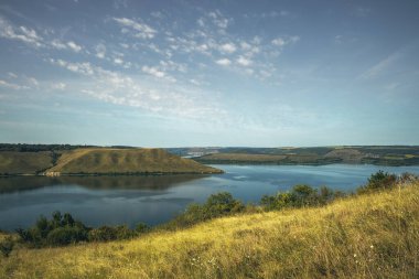 Basit doğa manzarası tepeleri göl kenarına iniyor sakin sular bulutlu bir yaz sabahı huzurlu manzarası