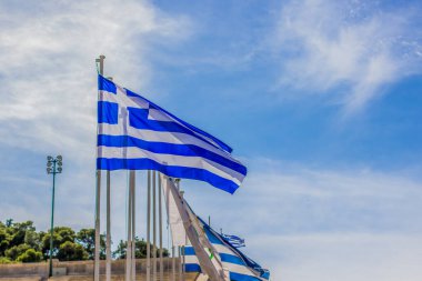 Yunanistan ulusal bayrağı, beyaz bulutların arka plan boşluğu ile mavi gökyüzünde rüzgarda evrimleşiyor