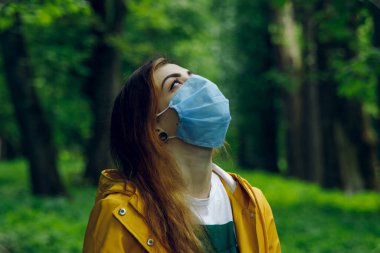Maskeli kadın portresi temiz hava solumak ve doğa, gerçek kirlilik ve korona virüsü kavramına bakmak istiyor.