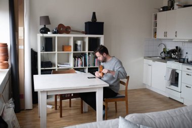 Telleri cep telefonu uygulaması ile değiştirdikten sonra banjo ukulele ayarlayan adam