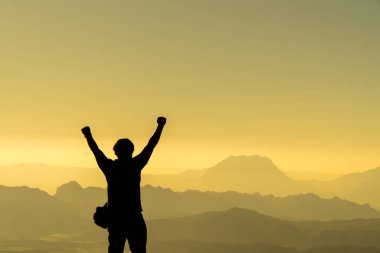 Gezgin adam sağ elini kaldırdı, dağlar manzara arka plan üzerinde iş için başarı liderlik siluet kavram kavramı, arka plan görünüm mockup, mavi renk tonu efekti üzerinde turist gezgin fethetmek