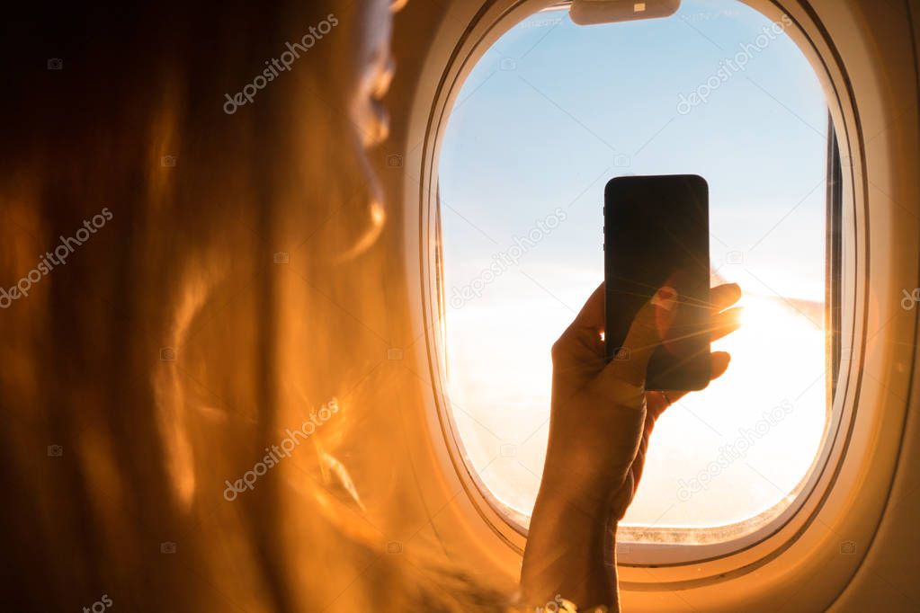 Taking photo on airplane,Travel accessories for snap moment,Hand holding Smart phone and take photograph,Camera for Travel accessories,Photography in the air.