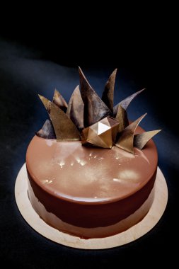 Trendy modern çikolatalı mousse kek ayna sır ve çikolata dekor ile dekore edilmiştir. Siyah arka plan.