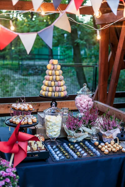 Čokoládu s lahodnou sladkostí, čokoládové bonbóny, macaron věží a jiné pochoutky v podzimním parku. Podzimní dekorace. Přirozené světlo — Stock fotografie