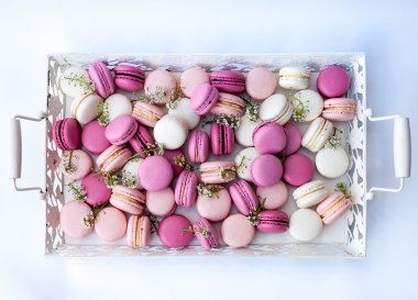 Beyaz tepsi tam renkli macarons pembe tonları. Doğal ışık. Seçici odak.