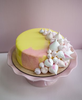 Pembe mousse kek sarı ve pembe çikolata ayna sır ve beze öpücük kaplı. Pembe porselen kürsüye. Pembe bir arka plan. Doğal ışık.