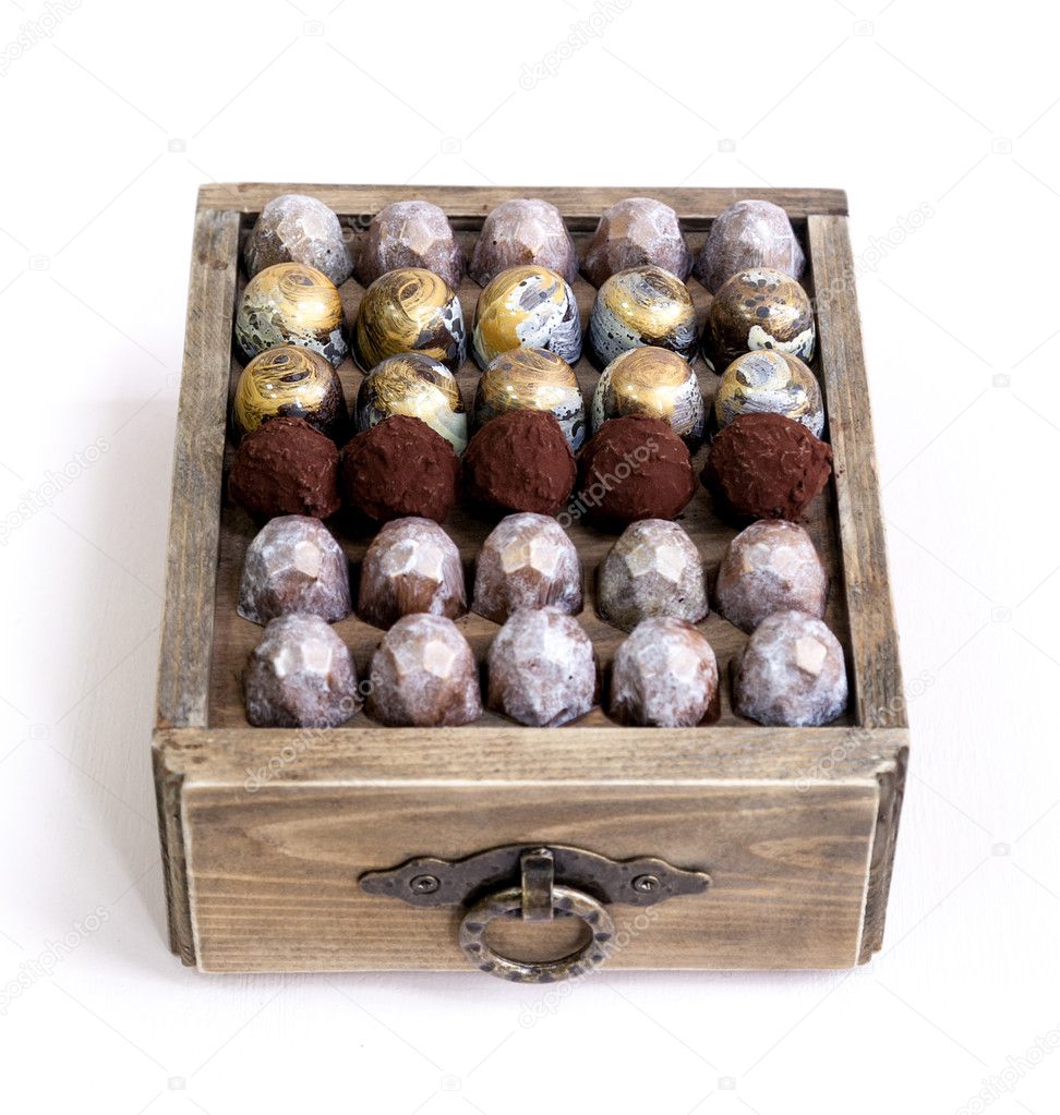 Chocolate hand made painted candy bonbons on a wooden box. Isolated on white. Natural light