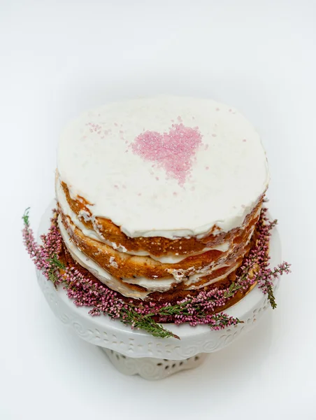 Zarte schäbige hausgemachte Torte mit einem rosa Herz oben und Heidekrautblüten unten. weißer Hintergrund — Stockfoto