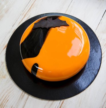 Cadılar Bayramı parlak turuncu ve siyah çikolata yarasa dekor ile pasta mousse. Ahşap arka plan