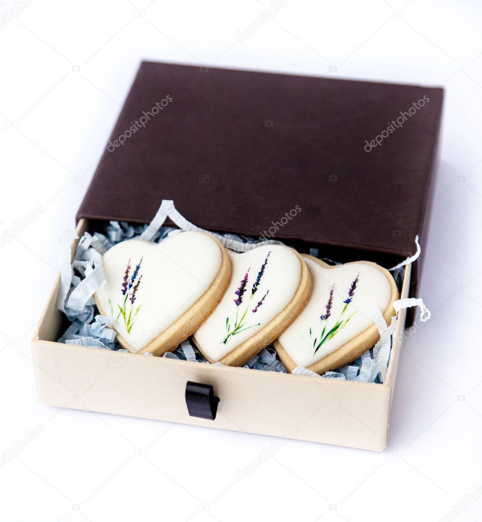 Hand painted cookies topped with white glaze in a gift box. Hand drawn with edible coloring lavender flower stems motive. Natural light