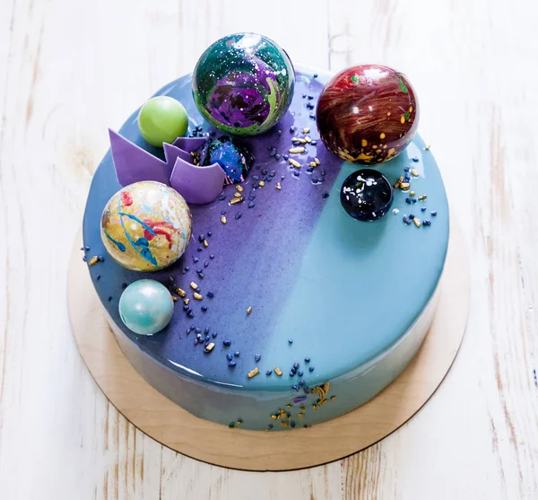 Modern trendy mousse cake with violet blue marble mirror glaze on a white background. Chocolate planet decor. — Stock Photo, Image