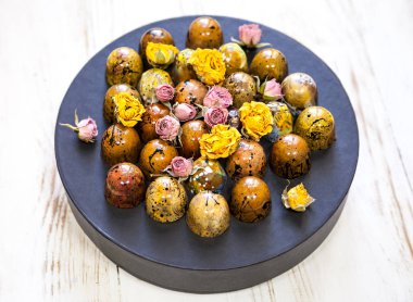 Çikolata lüks şeker bonbon siyah yuvarlak hediye kutusu üzerinde yapılmış. Kuru gül dekor. Ahşap arka plan.