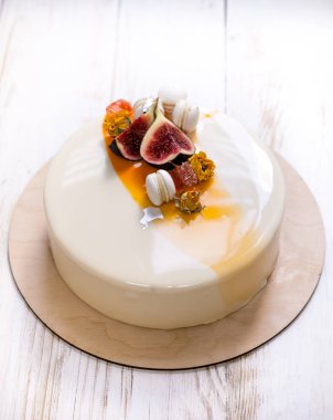 Menekşe beyaz ve turuncu ayna sır üzerinde beyaz bir arka plan ile minimalist mousse kek. Mini macaron, incir ve yenilebilir gümüş dekor. Ahşap arka plan