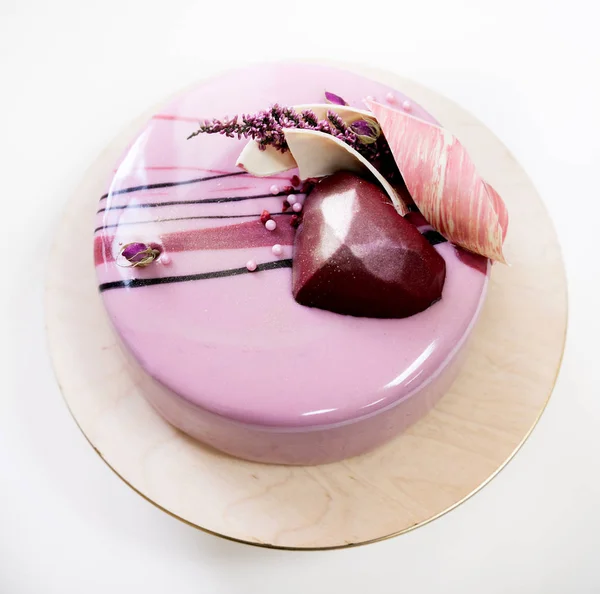 Minimalistischer rosa Moussekuchen mit Spiegelglasur auf weißem Hintergrund. Schokoladenherz, Schokoladenwirbel und trockene Heidekore. — Stockfoto