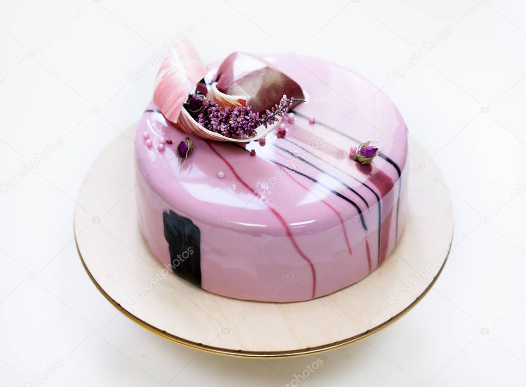 Minimalistic pink mousse cake with coated with mirror glaze on a white background. Chocolate heart, chocolate swirl and dry heather decor.