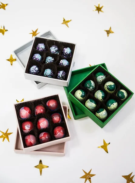 Chocolate handpainted luxury candy bonbons in a gift box. White background with golden stars. — Stock Photo, Image