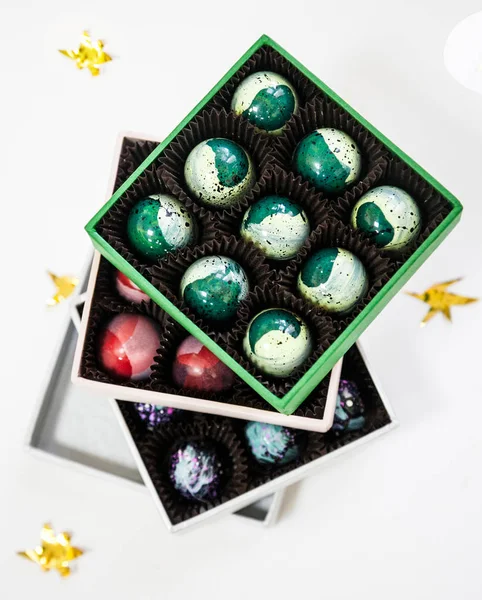 Chocolate handpainted luxury candy bonbons in a gift box. White background with golden stars. — Stock Photo, Image