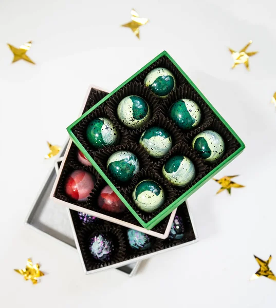 Bombones de caramelo de lujo pintados a mano de chocolate en una caja de regalo. Fondo blanco con estrellas doradas . — Foto de Stock