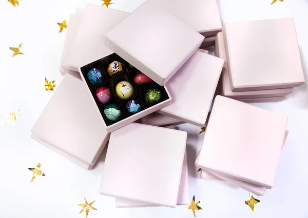 Σοκολάτας καραμέλες καραμέλα πολυτέλεια σε ένα ροζ δώρο κουτιά Χειροποίητη. Λευκό φόντο με χρυσά αστέρια. — Φωτογραφία Αρχείου