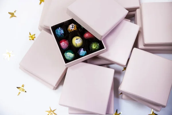 Σοκολάτας καραμέλες καραμέλα πολυτέλεια σε ένα ροζ δώρο κουτιά Χειροποίητη. Λευκό φόντο με χρυσά αστέρια. — Φωτογραφία Αρχείου