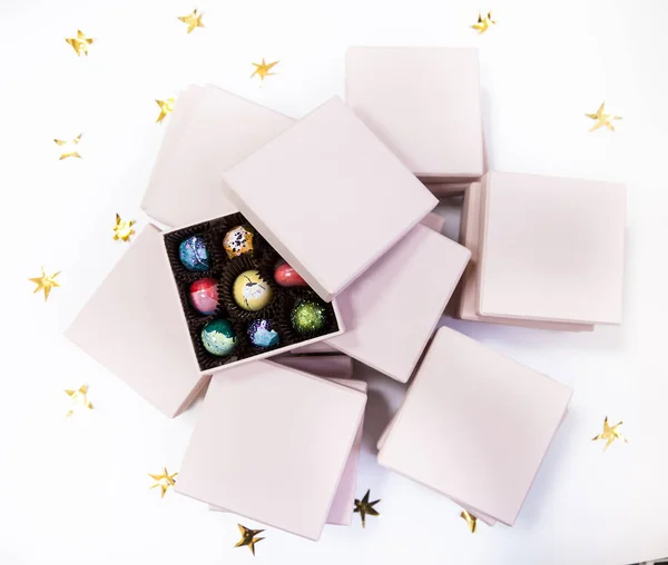 Çikolata el lüks şeker bonbon pembe hediye kutuları içinde boyalı. Altın yıldız ile beyaz arka plan. — Stok fotoğraf