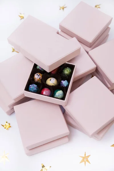 Çikolata el lüks şeker bonbon pembe hediye kutuları içinde boyalı. Altın yıldız ile beyaz arka plan. — Stok fotoğraf