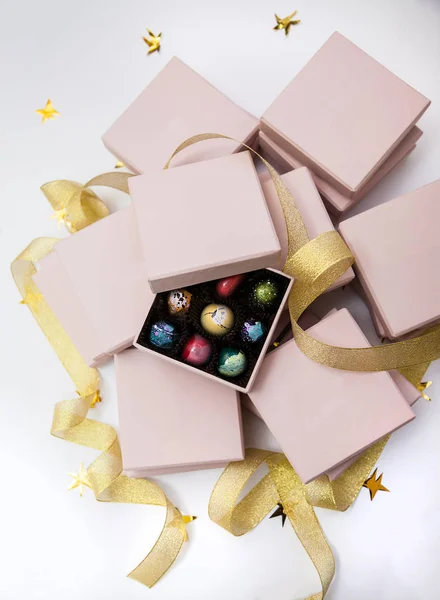 Çikolata el boyalı lüks şeker bonbon pembe bir hediye kutuları ve altın şerit. Altın yıldız ile beyaz arka plan. — Stok fotoğraf