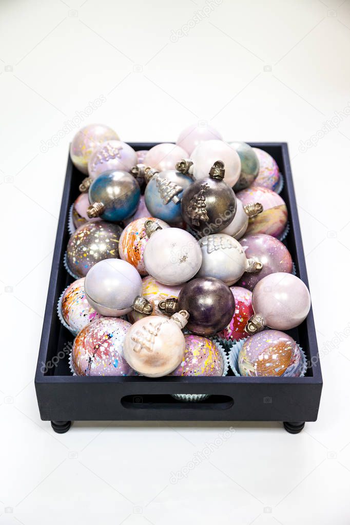 Christmas hand painted chocolate candy balls and on a wooden black tray.