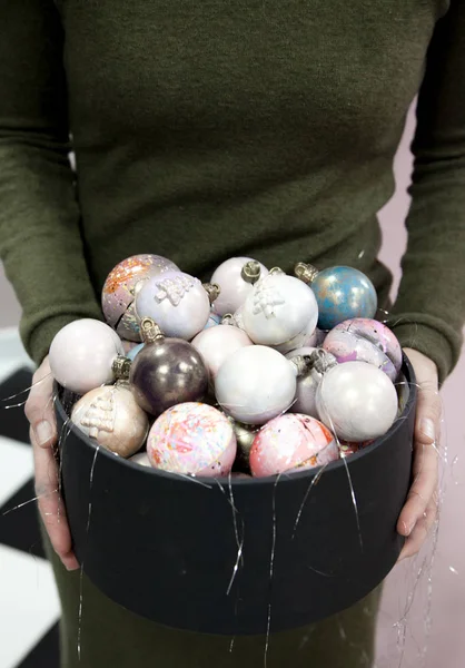 Manos sosteniendo bolas de chocolate pintadas a mano de Navidad en una caja de regalo negra . — Foto de Stock