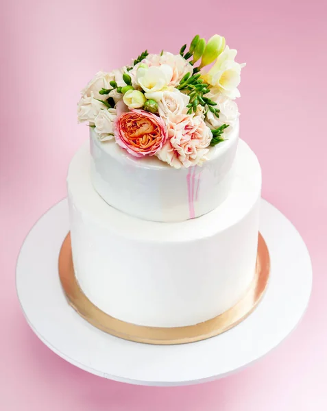 Elegant wedding tiered cake decorated with fresh roses and freesia