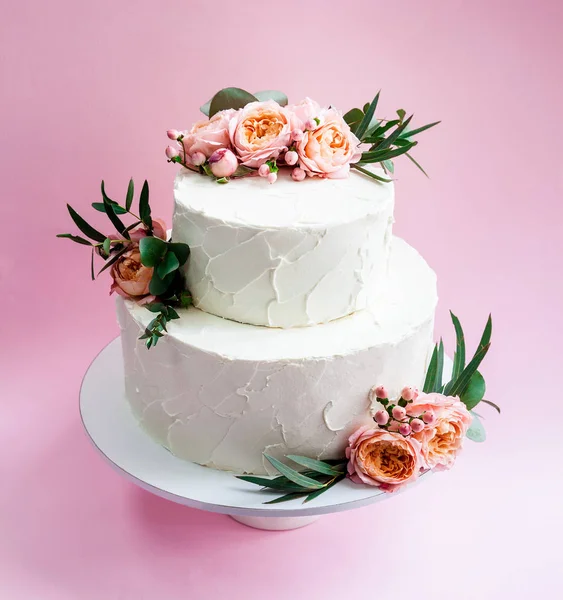 Elegant wedding tiered cake decorated with fresh roses and freesia