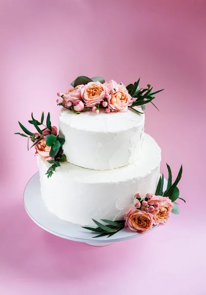 Elegant wedding tiered cake decorated with fresh roses and freesia