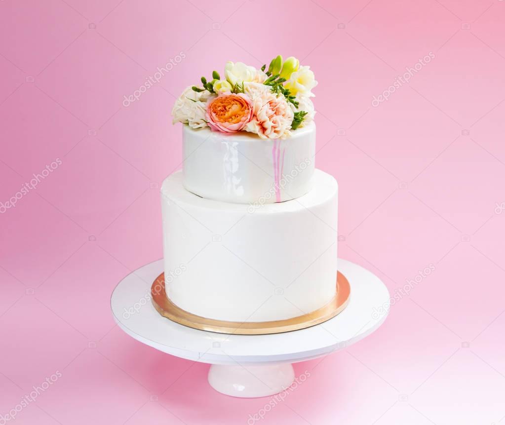 Elegant wedding tiered cake decorated with fresh roses and freesia