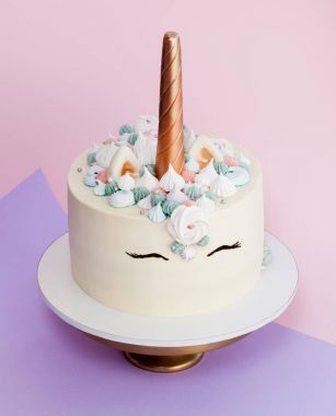 Tek boynuzlu at meringues ile dekore kek katmanlı. Pembe bir arka plan.