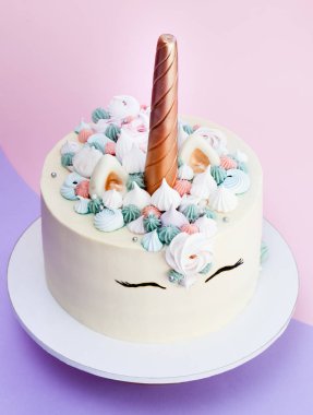 Tek boynuzlu at meringues ile dekore kek katmanlı. Pembe bir arka plan.