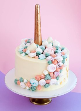 Tek boynuzlu at meringues ile dekore kek katmanlı. Pembe bir arka plan.