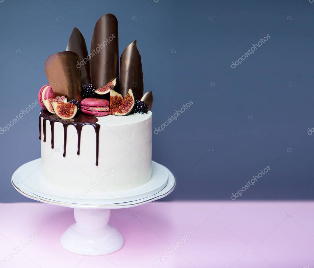 Cake decorated with chocolate waves, pink macaron and fresh figs