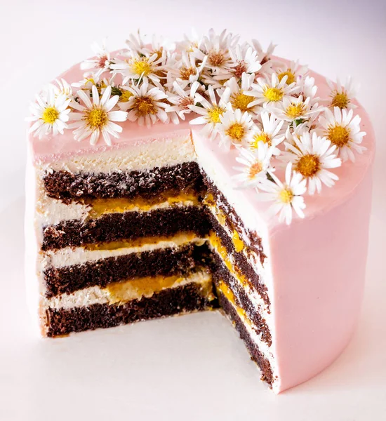 デイジーの花で飾られたチョコレート マンゴー ケーキをスライス — ストック写真
