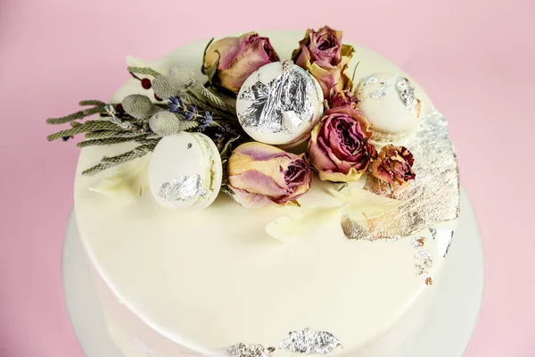 Mousse cake decorated with macaron and roses. Pink background