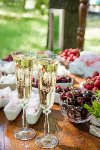 Feestelijke tafel instelling wijnglazen met champagne, fruit en marshmallows. Bruiloft decor. — Stockfoto