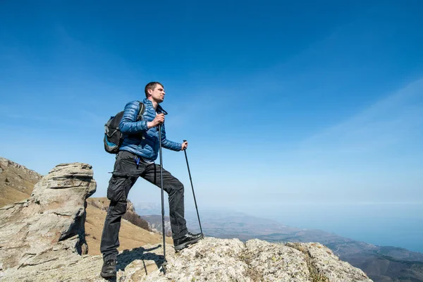 Viajero con bastones de trekking y una mochila en la cima de la montaña —  Fotos de Stock