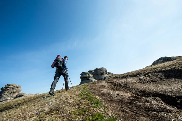 Viaggiatore con bastoncini da trekking e zaino in spalla passeggiate in montagna — Foto Stock