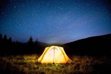 Yıldızlı gökyüzü altında gece dağ ormanda kamp çadır parlayan