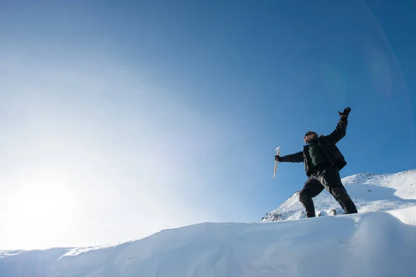 Happy climber with an ice ax in the snowy mountains — Stock Photo, Image