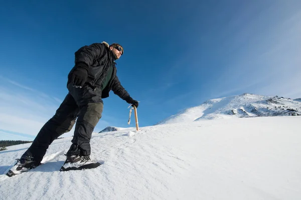 Klimmer met een ijsbijl in de besneeuwde bergen — Stockfoto