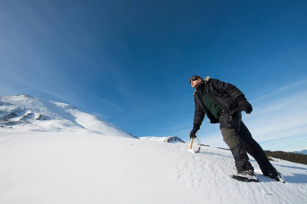 Klimmer met een ijsbijl in de besneeuwde bergen — Stockfoto