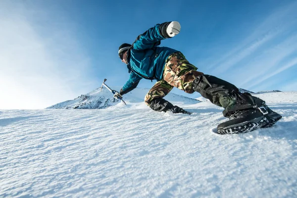 Escalador com um machado de gelo subir na montanha nevada — Fotografia de Stock