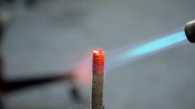 Gaz ocağı alevi, metal civatayı kızıştırıyor.